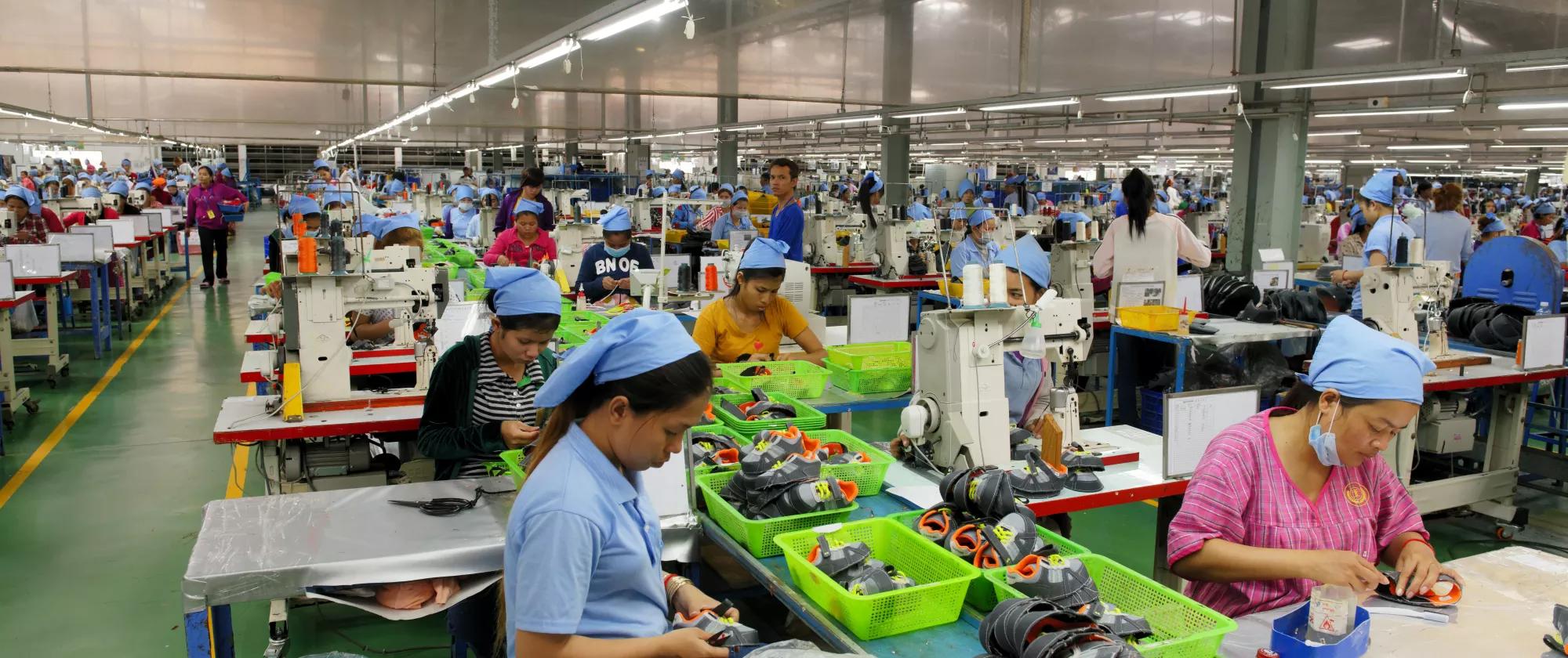 Workers produce footwear on a factory floor in Cambodia