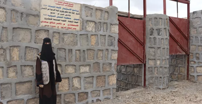 a female contractor standing in front of a project signboard