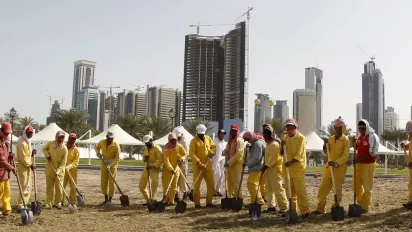 Migrant workers dig into a field in Doha, Qatar