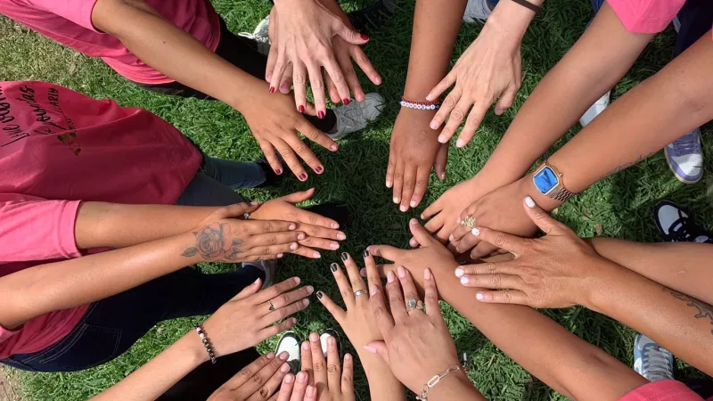 Manos de mujeres juntas en señal de trabajo en equipo