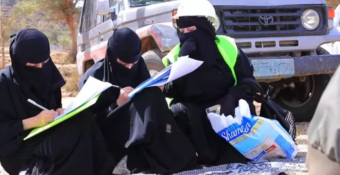 3 veiled women working on maps of a contracting project