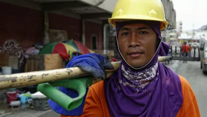 Worker using protective equipment to clear and remove debris after Typhoon Haiyan (Yolanda) in the Philippines.